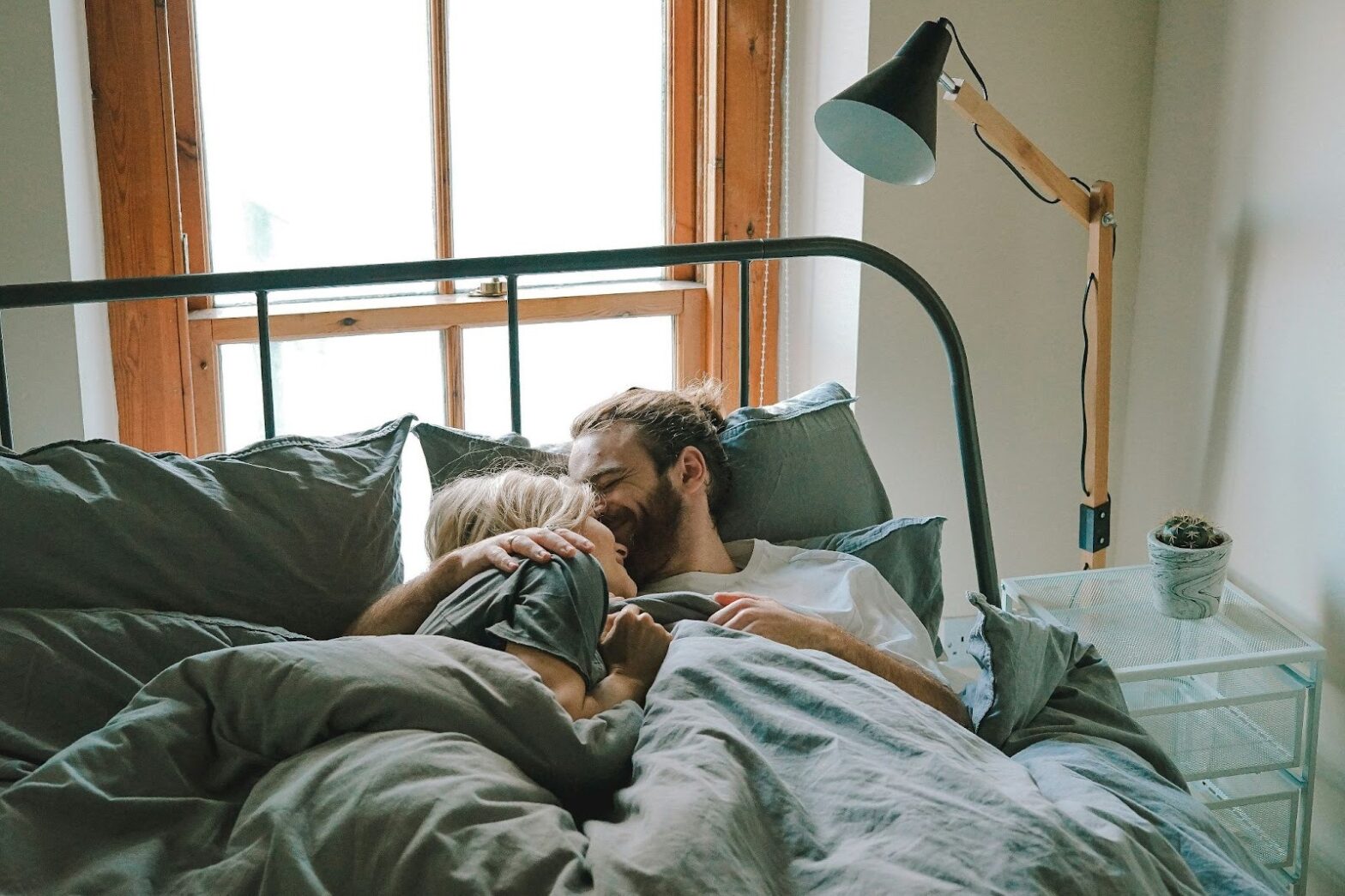 Couple sharing a warm, intimate moment in bed, reflecting emotional safety, trust, and deep connection