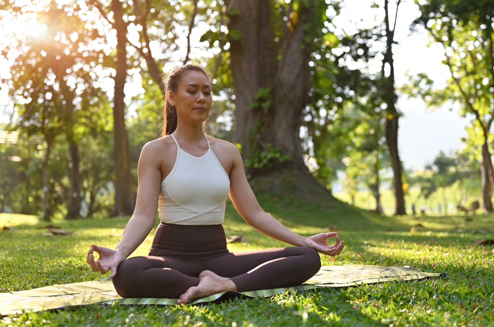 Woman practicing mindful meditation outdoors, sitting calmly to build emotional balance, inner peace, and resilience