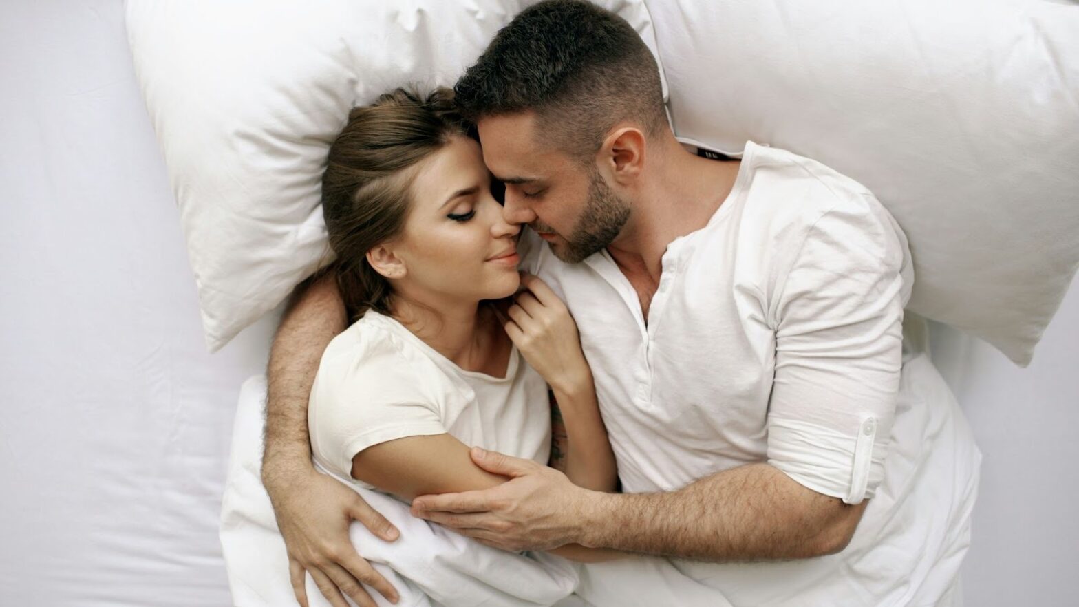 a couple intimately embracing and cuddling in bed.