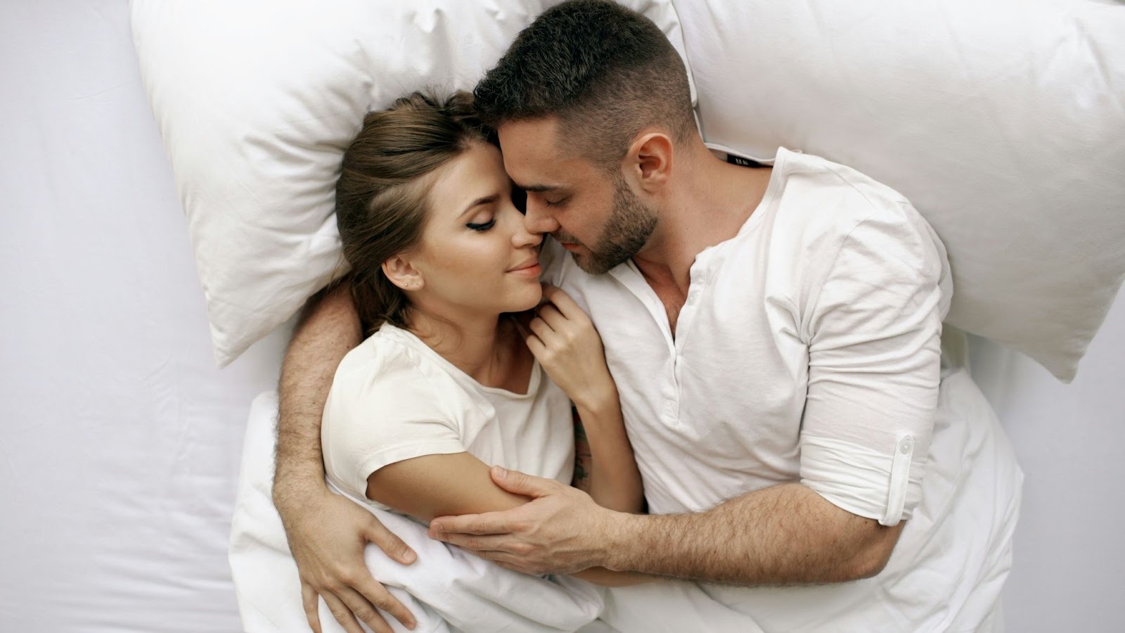 a couple intimately embracing and cuddling in bed.