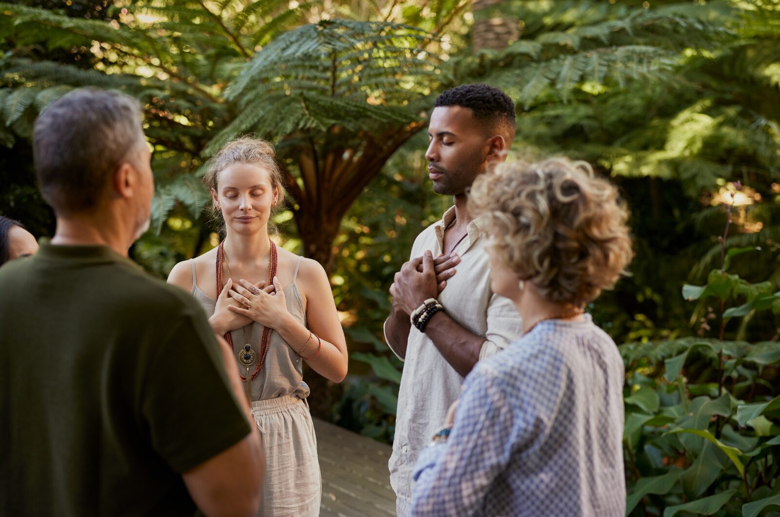 Group practicing gratitude meditation outdoors, hands on heart, reflecting thankful heart and mindful happiness