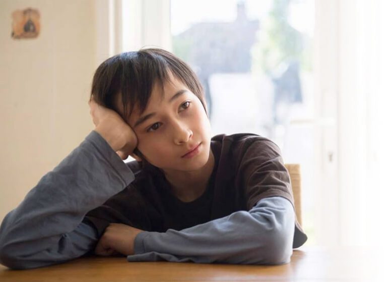 A thoughtful teenage girl sitting at a table, lost in reflection, symbolizing emotional growth and self-discovery.