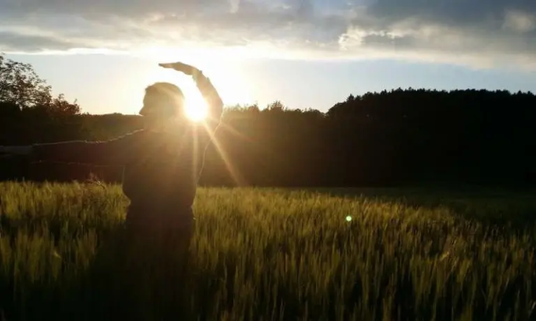 Person embracing sunrise in a field, symbolizing reflection, renewal, and intention for the year ahead.