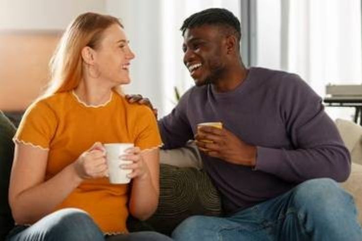 Happy couple engaging in Imago relationship therapy session, sharing laughter and connection during communication exercise