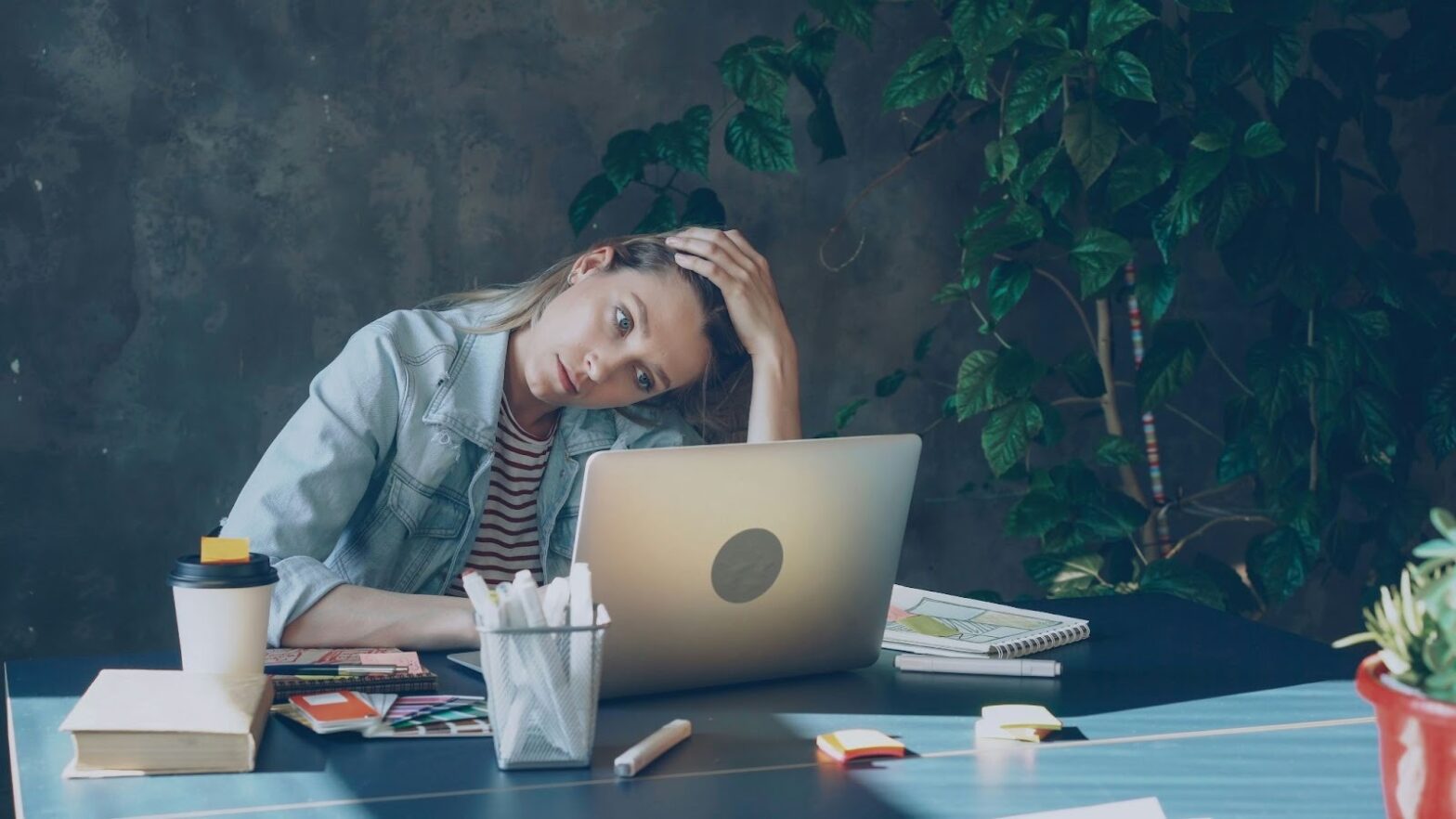 Young woman showing signs of emotional burnout while working on a laptop, feeling stressed and mentally exhausted.