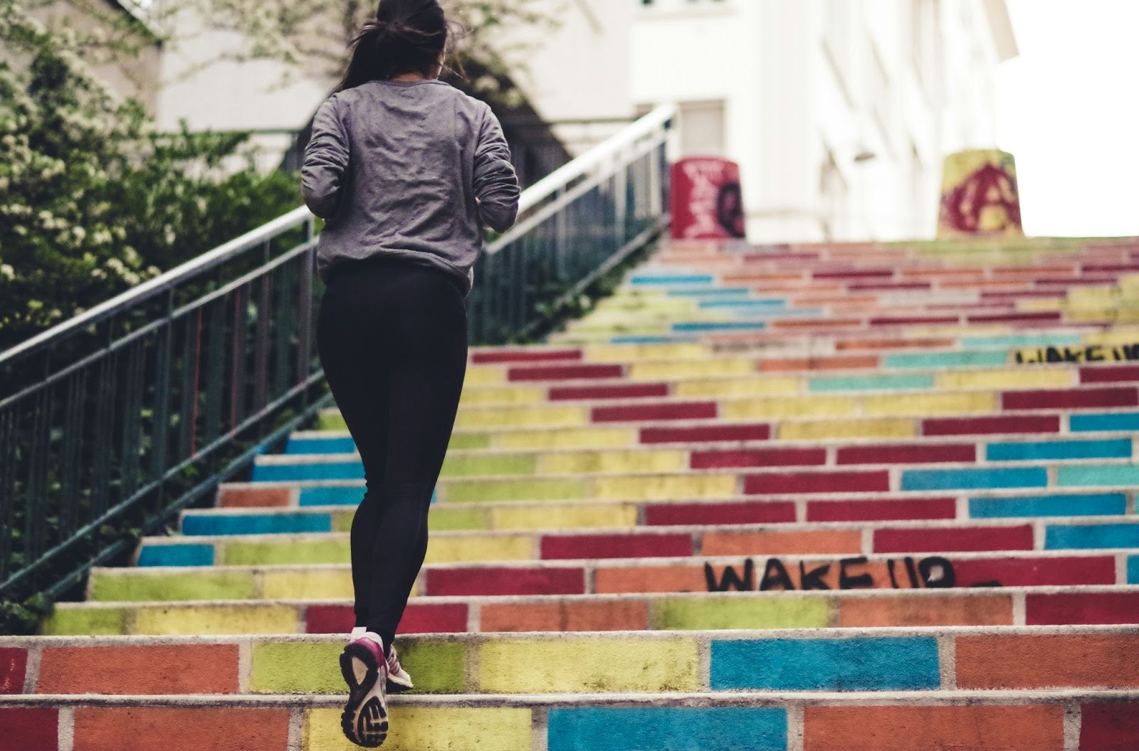 A woman runs up bright rainbow stairs, representing step-by-step progress and tracking personal therapy goals.