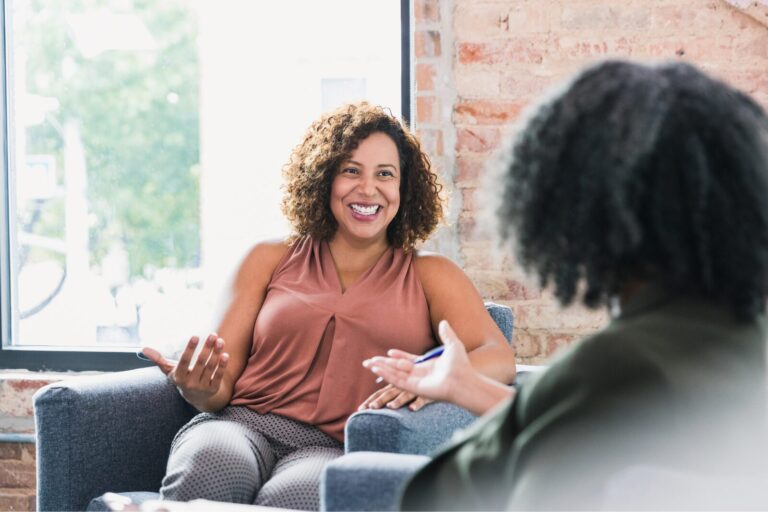 Smiling woman talks openly with therapist during first therapy session, easing anxiety and building trust.