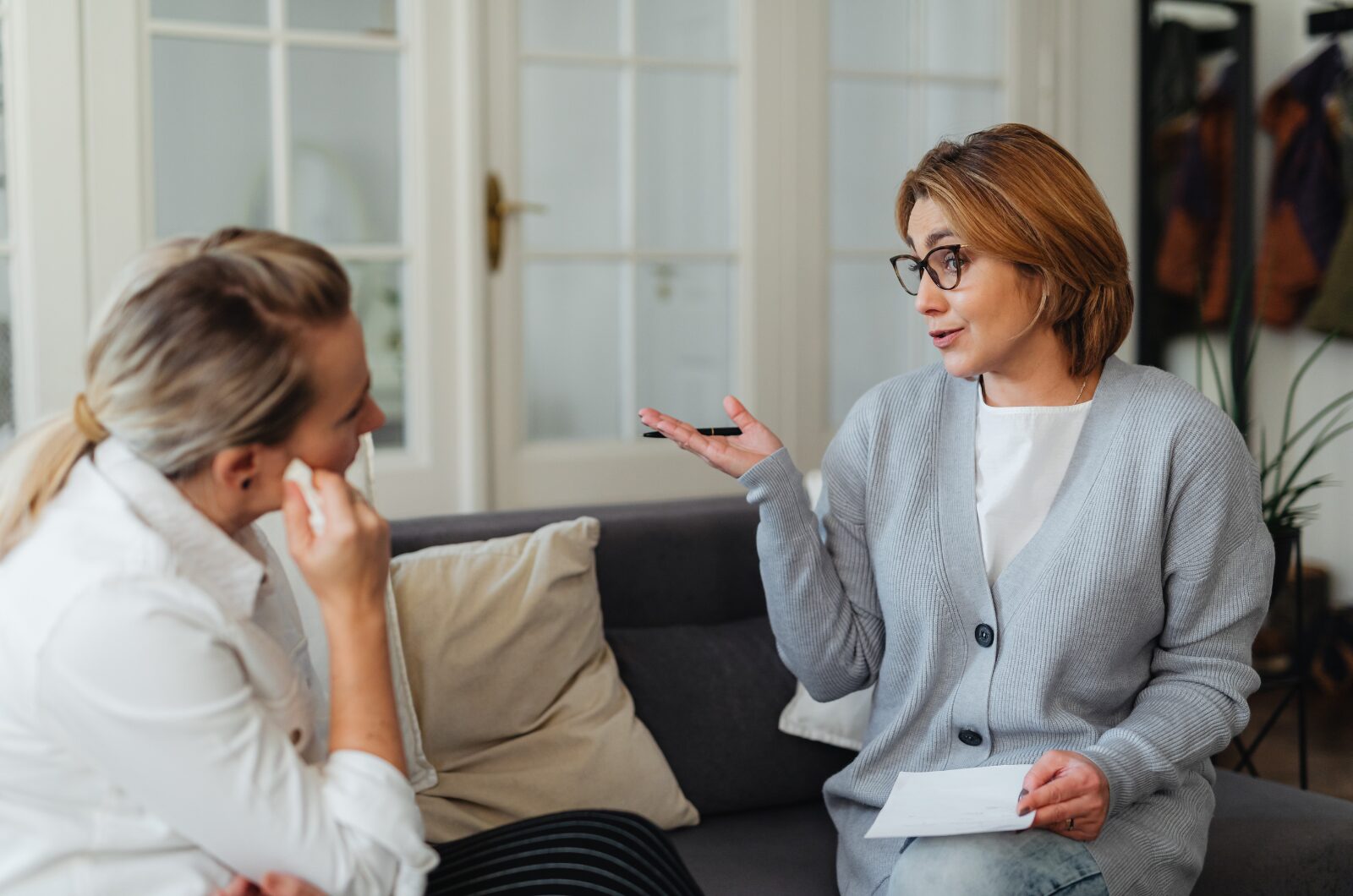 Navigating Life Transition in San Diego: How Therapy Can Help You Thrive Therapist gently guiding a woman who is wiping tears during an emotional counseling session in a calm, supportive setting.
