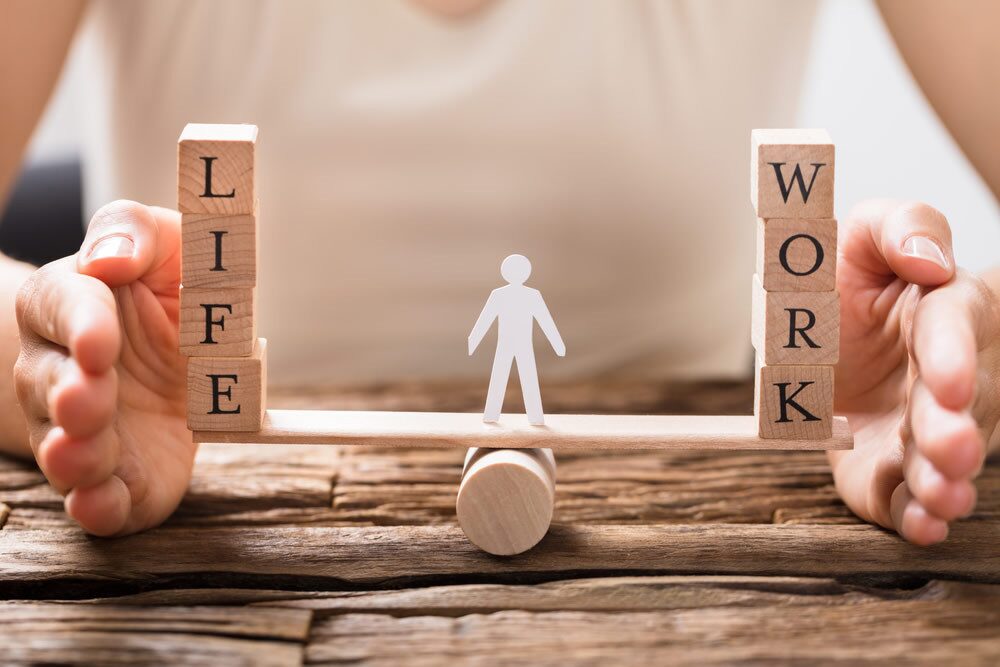 Wooden blocks showing life-work balance with a figure in the center symbolizing managing stress and well-being in San Diego.