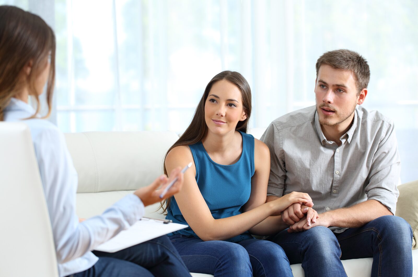 Couple in Imago relationship therapy session, holding hands while therapist guides open communication and healing