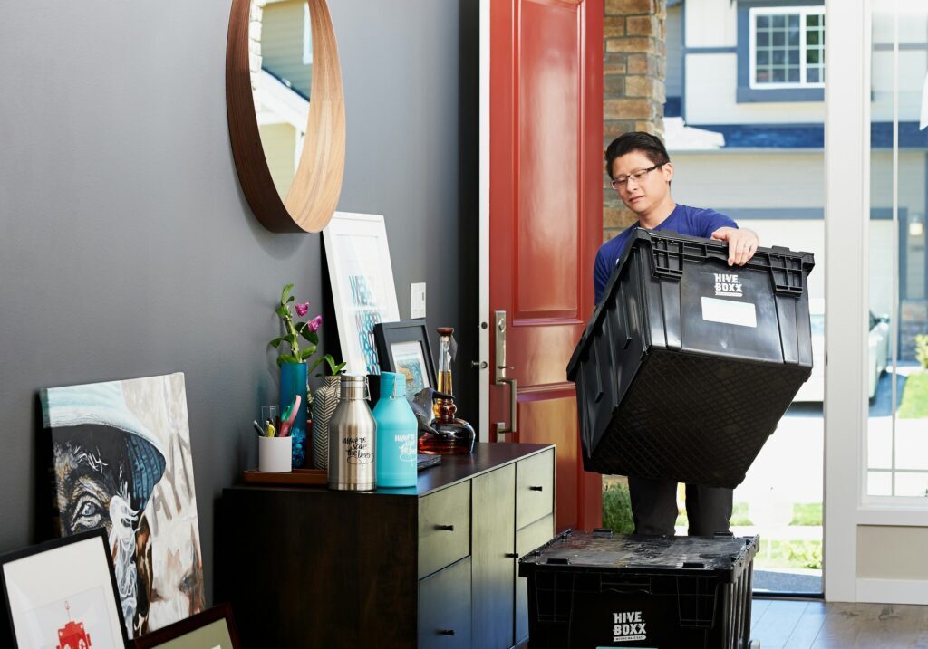 Man carrying moving boxes while relocating to a new home, symbolizing life transitions, career change, and fresh beginnings
