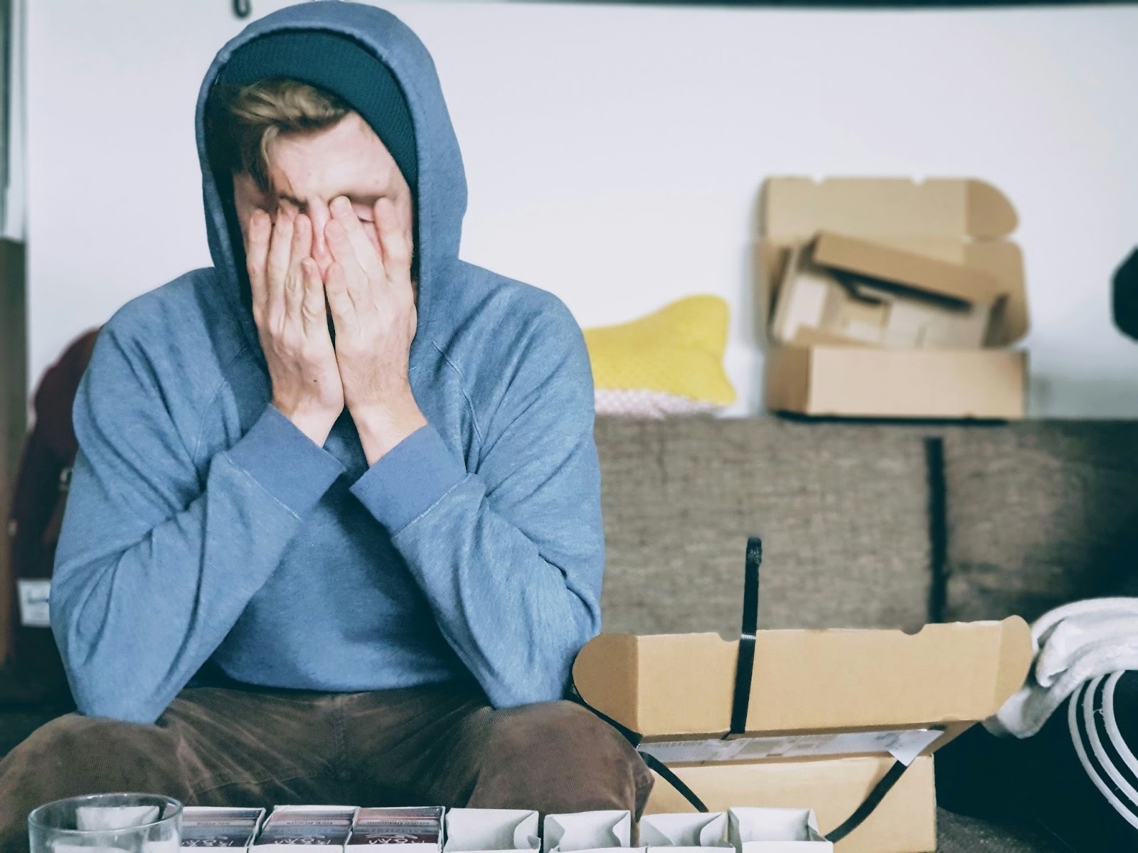 Stressed man sitting on couch with face covered, showing mental overload and mind body disconnection