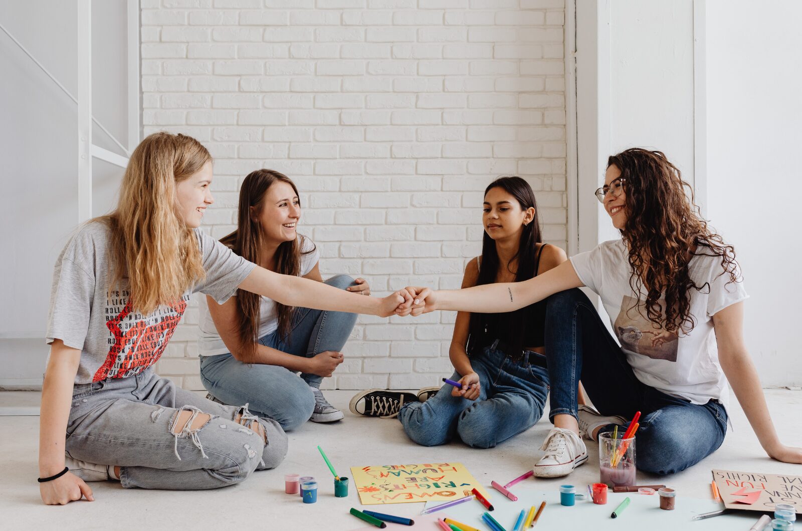A group of teenage girls bonding and expressing emotions together in a supportive teen therapy group activity