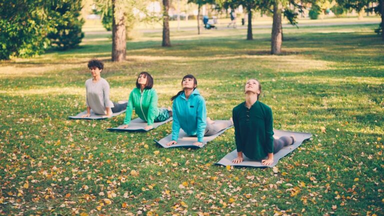 Group practicing yoga outdoors to reduce stress, relax the body, and support mental calm and balance